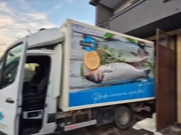 Bijeli dostavni kamion sa velikom fotografijom ribe i limuna na sanduku