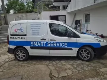 Bijeli kombi Smart Service sa plavom trakom i natpisom na boku