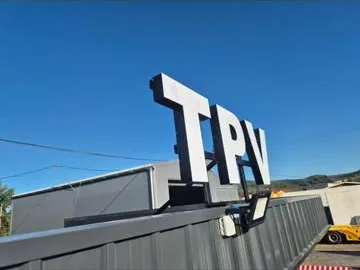 Velika bijela 3D slova TPV na krovu objekta, ispod plavog neba